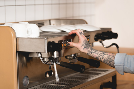 Cropped view of tattooed barista preparing coffee on espresso machineの写真素材