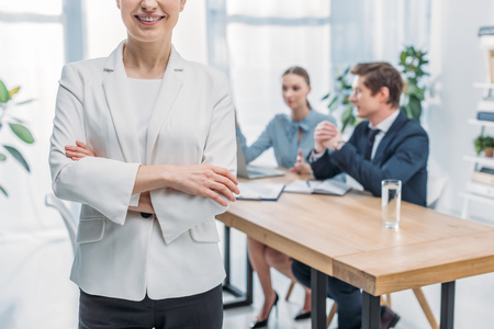 Cropped view of cheerful recruiter standing with crossed arms near coworkersの写真素材
