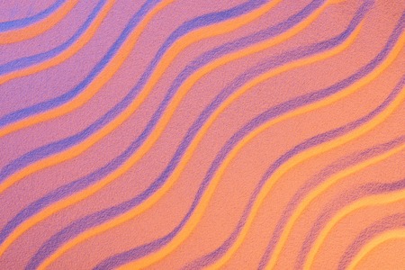 top view of textured sand with smooth waves and neon pink color filterの写真素材