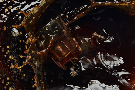 Overturned glass with black coffee, big splash and dropsの写真素材