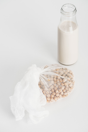 Chickpea in white cheesecloth near bottle with vegan chickpea milk on grey backgroundの写真素材
