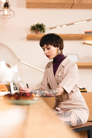 Selective focus of pretty businesswoman sitting at bar counter in cafeの写真素材