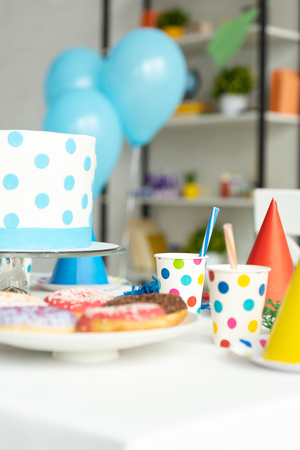 Selective focus of birthday cake, donuts and party decorations on tableの写真素材