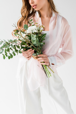 Cropped view of girl holding flowers with green eucalyptus leaves on white backgroundの写真素材