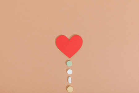 Top view of paper heart and pills on brown surfaceの写真素材