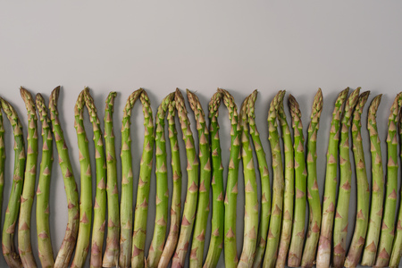 Top view of green raw asparagus in row on grey backgroundの写真素材