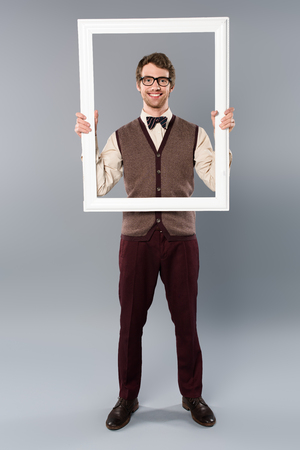 Happy man holding white frame on grey backgroundの写真素材