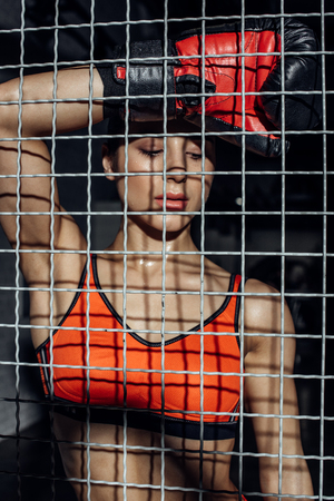Attractive boxer standing behind wire netting and looking downの写真素材