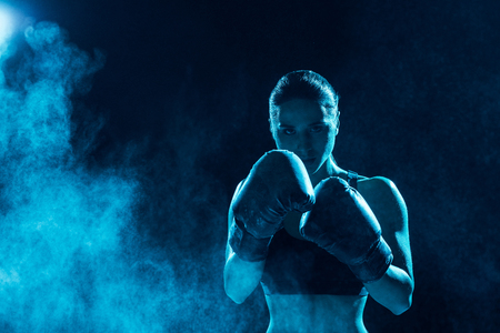 Front view of serious boxer in boxing gloves looking at cameraの写真素材