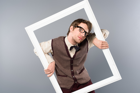 Funny man holding white frame on grey background