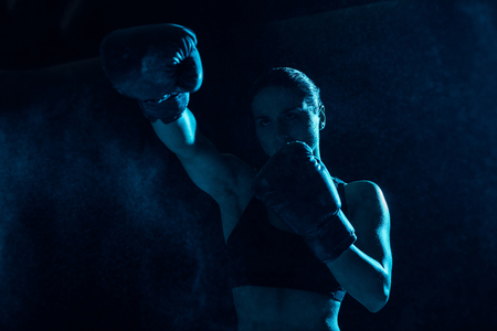 Serious boxer in boxing gloves training and looking awayの写真素材