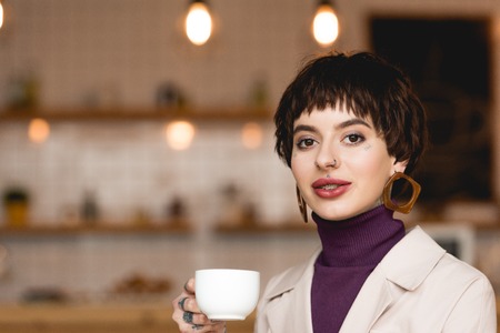 Beautiful businesswoman holding coffee cup, smiling and looking at cameraの写真素材