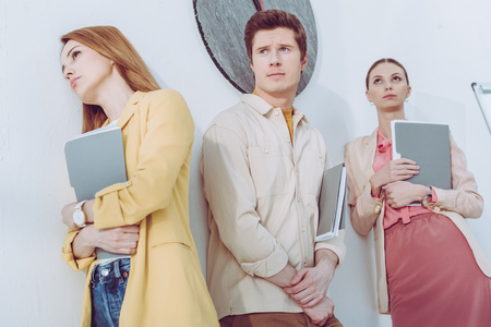 Low angle view of women and handsome man waiting in line with folders