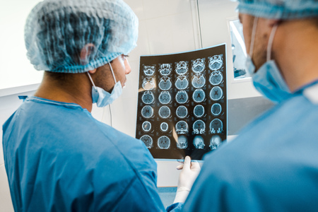 Back view of doctors in uniforms and medical masks looking at x-rayの写真素材