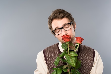 Joyful man in glasses with closed eyes smelling bouquet of rosesの写真素材