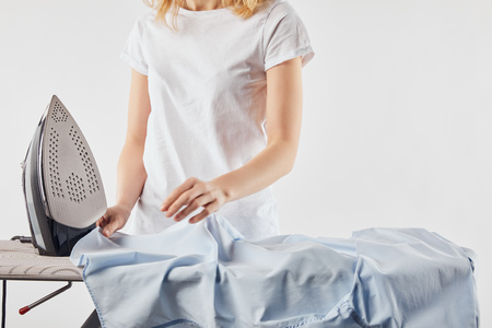 Cropped view of girl ironing blue shirt isolated on white backgroundの写真素材
