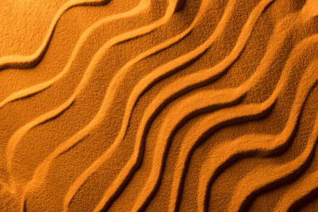Top view of sandy background with smooth waves and orange color filterの写真素材