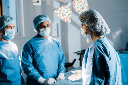 Selective focus of doctors and nurse in uniforms and medical masks talking