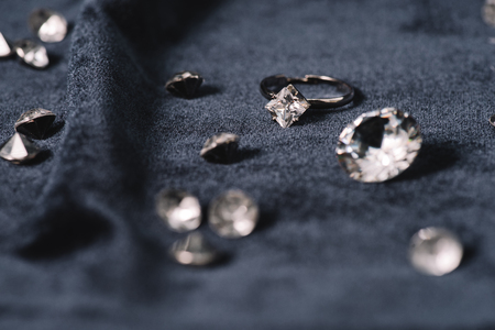 Selective focus of engagement ring near shiny diamonds on blue clothの写真素材