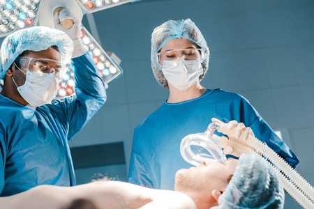 Selective focus of patient, doctor and nurse in uniforms and medical caps holding maskの写真素材