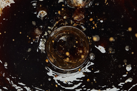 Top view of glass and black coffee with drops