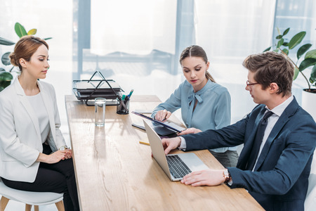 recruiter looking at laptop near coworker and women on job interview