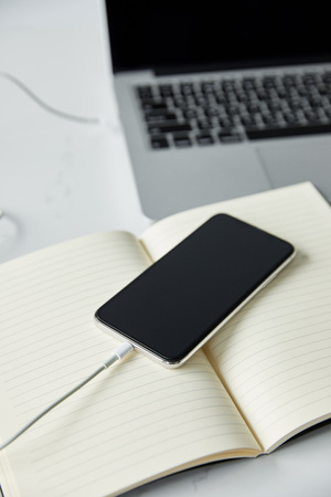 Selective focus of smartphone with blank screen, notebook and laptop on white surfaceの写真素材