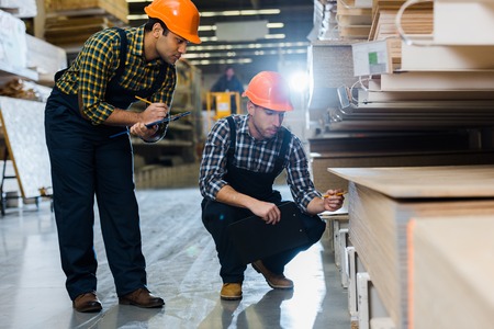 Two multicultural colleagues in uniform and helmets working in warehouseの写真素材