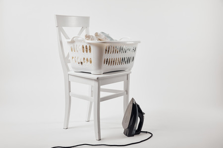 White chair, laundry basket with clothes and iron on grey backgroundの写真素材