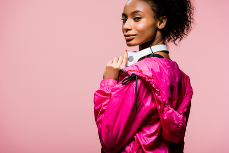 Beautiful African American sportswoman with headphones looking at camera isolated on pink with copy spaceの写真素材