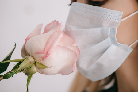Cropped view of woman in medical mask smelling roseの写真素材