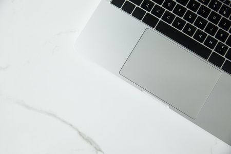 top view of laptop with black keyboard on white marble surface