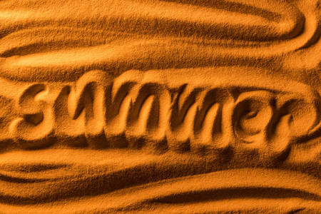 Top view of word summer written in sand with smooth waves and color filterの写真素材