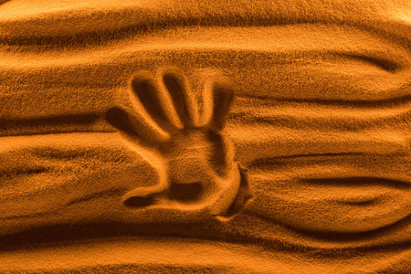 Top view of hand mark on sand with color filter and smooth wavesの写真素材