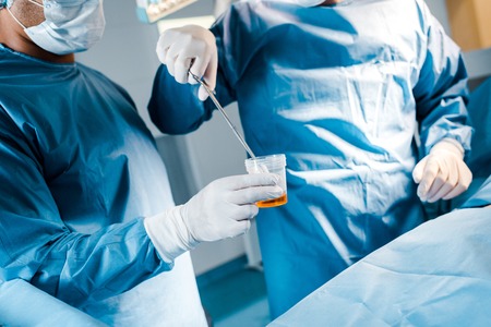 Cropped view of surgeon putting tampon to iodine in operating room