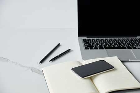 Selective focus of smartphone on notebook, and laptop with blank screen isolated on grey backgroundの写真素材