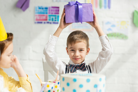 selective focus of boy holding present and looking at camera during birthday partyの写真素材