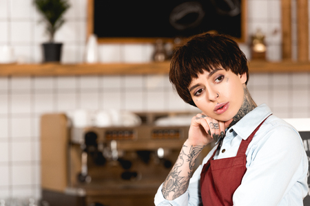 selective focus of pretty, dreamy barista holding hand near face and looking awayの写真素材