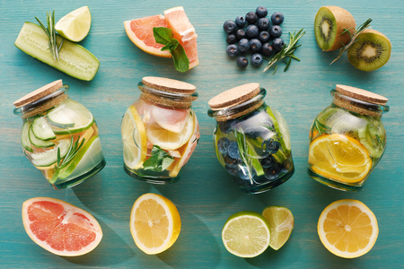 top view of detox drinks in jars with fruit ingredients on wooden surfaceの写真素材
