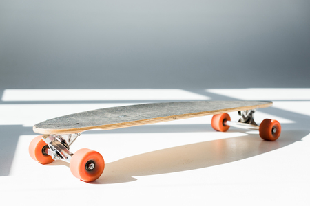 selective focus of longboard in sunlight with shadows on greyの写真素材