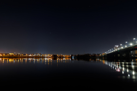 Dark cityscape with buildings, bridge, lights, river and night skyの写真素材