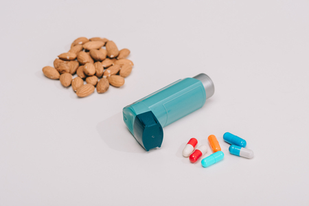 selective focus of pills and blue inhaler and tasty almonds near on greyの写真素材
