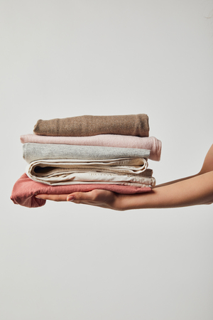 Cropped view of woman holding folded ironed clothes isolated on greyの写真素材