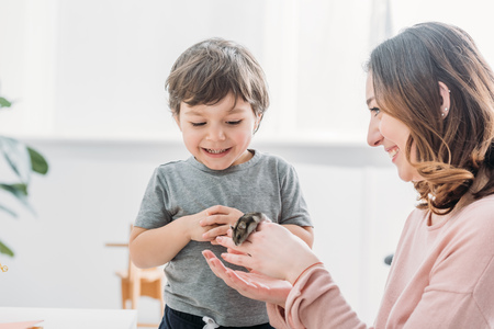 cheerful woman holding cute hamster near smiling adorable sonの写真素材