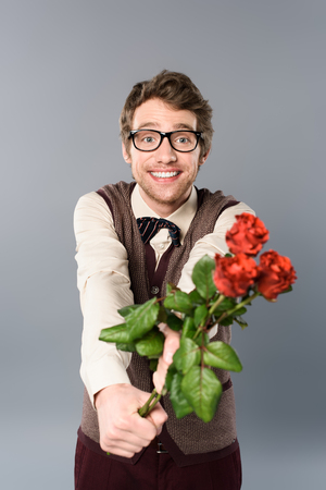 smiling man in glasses gifting bouquet of rosesの写真素材