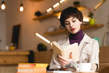 attractive businesswoman reading book while sitting in cafeの写真素材