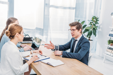 Handsome employee in glasses talking and gesturing on job interviewの写真素材