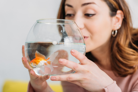 beautiful young woman holding fish bowl with bright golden fishの写真素材