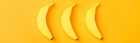 panoramic shot of arranged yellow paper bananas on orangeの写真素材