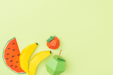 top view of colorful origami bananas, apple, strawberry and watermelon isolated on green with copy spaceの写真素材